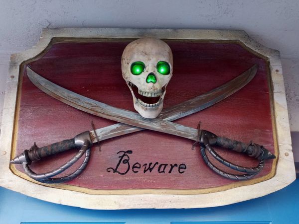 A pirate warning sign with glowing green-eyed skull and crossed swords.