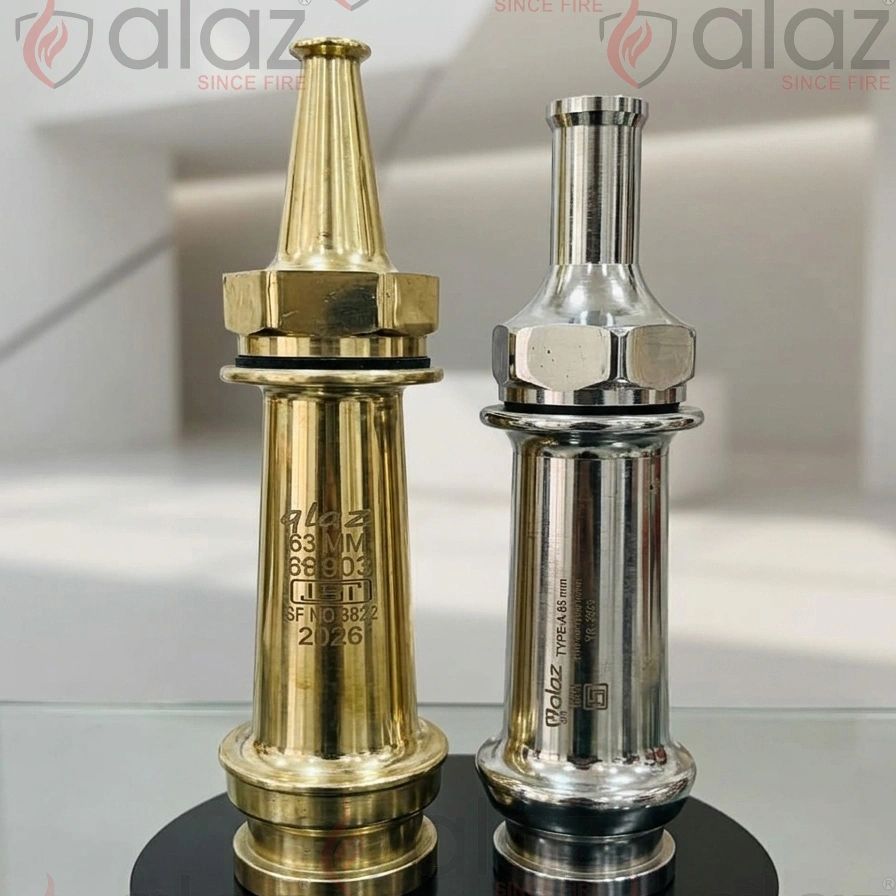 Two shiny fire hose nozzles, one brass and one silver, displayed on a reflective surface.