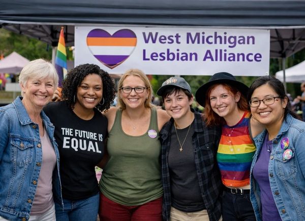 Group of six diverse women smiling at West Michigan Lesbian Alliance event.