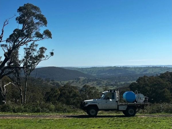 Pickup truck parked on green field with hills and blue sky.