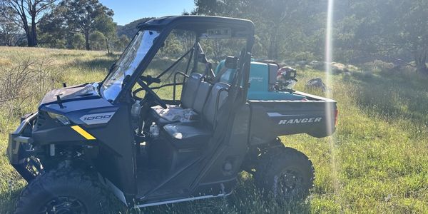 Utility terrain vehicle parked on grassy field in sunny weather.
