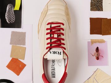 White sneaker with red laces and fabric swatches.