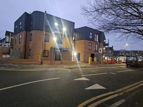 Modern brick building with bright lights on a quiet street at dusk.