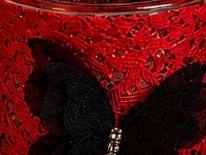 Close-up of a black butterfly on a red textured surface.