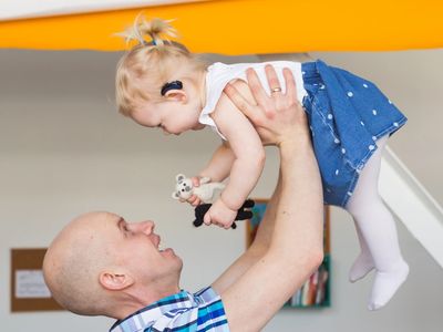 A man is holding a young child up in the air. 