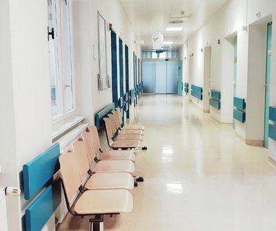 An empty hosiptal corridor with empty seats. 