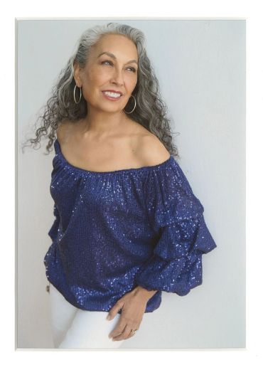 Smiling woman in a blue sequined off-shoulder top.