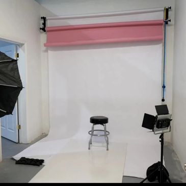 Empty photography studio setup with stool and lights.