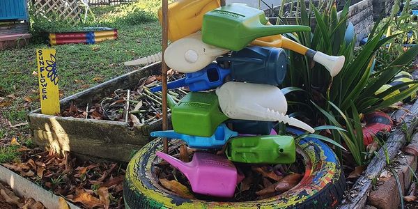 stack of watering  cans in a garden 