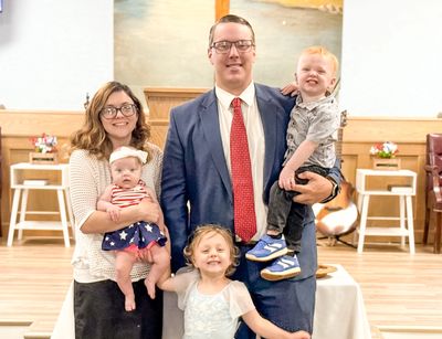 Family portrait with parents and three children indoors.