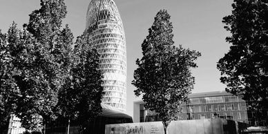 Black and white cityscape with a unique cylindrical building and trees.
