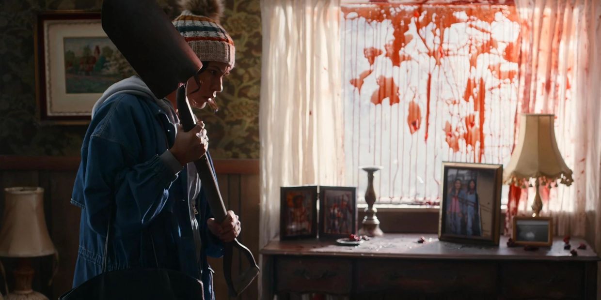 Person holding a shovel near a blood-splattered window.