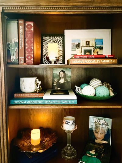 A wooden bookshelf with books, art, candles, and decorative items.