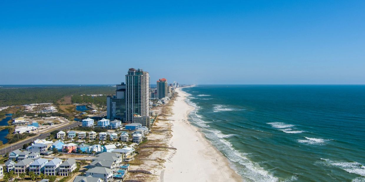 Aerial view of a coastal city with tall buildings and a sandy beach.
