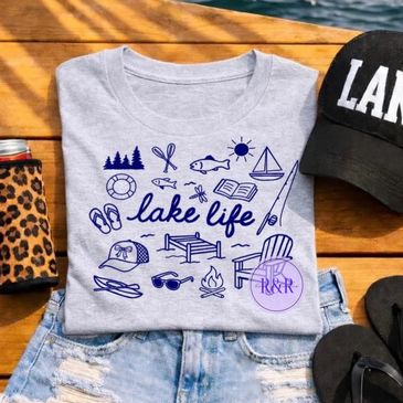 Gray t-shirt with blue lake life icons and text, paired with denim shorts and accessories.
