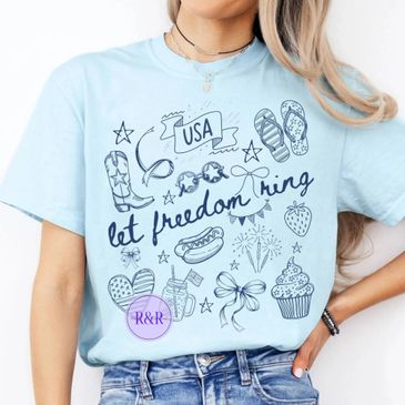 Light blue t-shirt with USA and freedom-themed doodles and text.