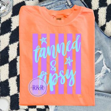 Orange T-shirt with "tanned &amp; tipsy" graphic design in blue and purple.