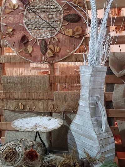 Decorative rustic wall art with a large white vase and dried natural elements.