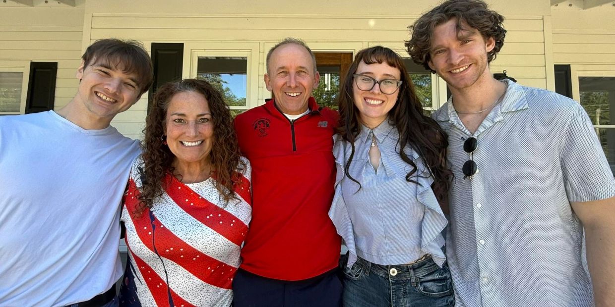 Five people smiling in front of a house.