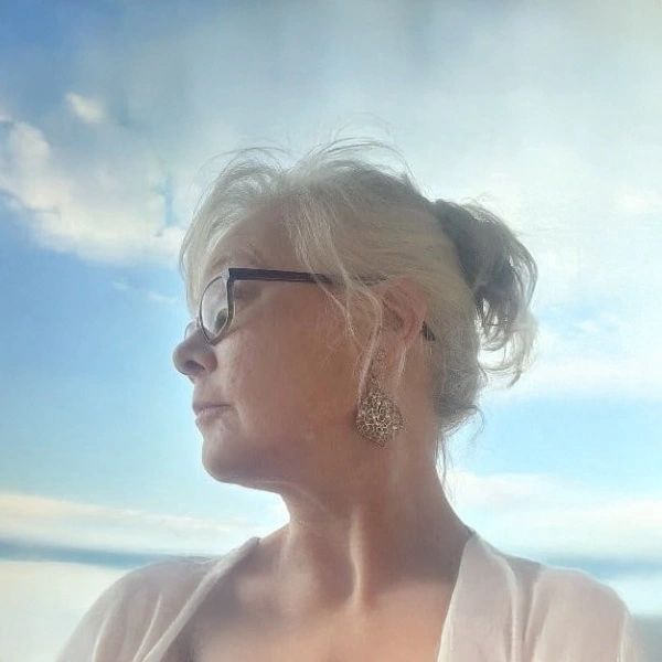Woman looking sideways outside with blue sky background.