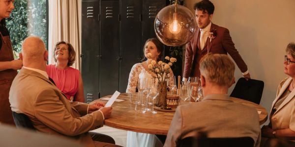 Mensen in gesprek rondom een tafel bij een formeel evenement.