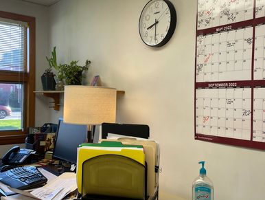 Organized office desk with a clock, calendar, and hand sanitizer.
