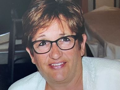 Smiling woman wearing glasses and a white sweater.
