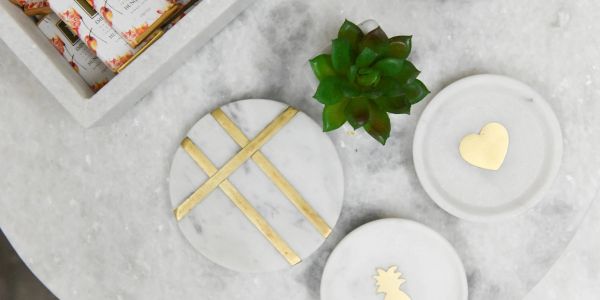 Marble trays with golden accents and a small green succulent on a gray surface.