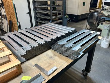 Stack of laser-cut and formed steel parts on a work table
