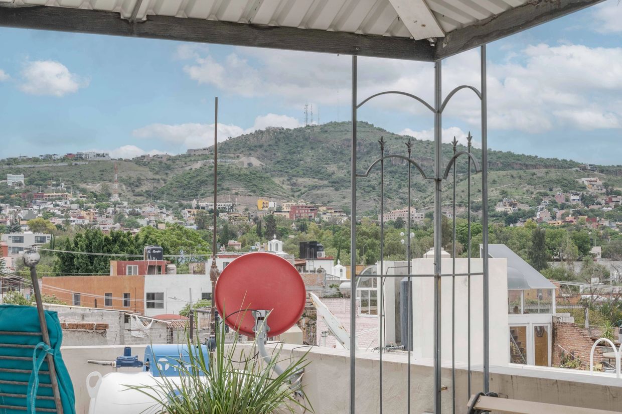 View from a rooftop terrace overlooking a city with hills in the background.