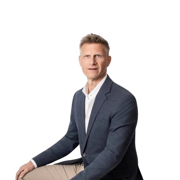 Professional man in a blazer sitting against a white background.