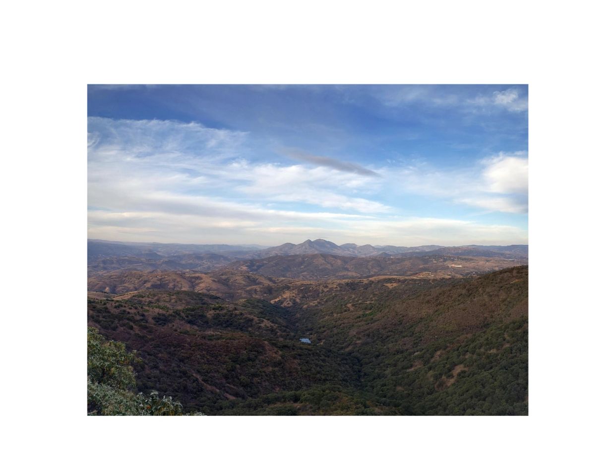 Vista panorámica de montañas y colinas bajo un cielo parcialmente nublado.