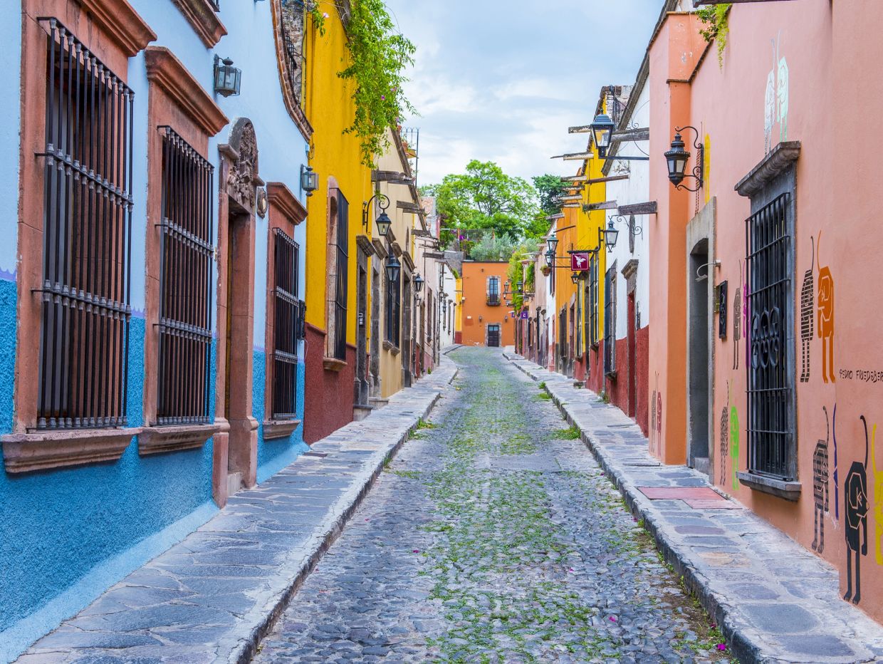 Colorful cobblestone street with vibrant buildings and wrought iron windows.
