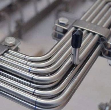 Close-up of neatly bent stainless steel tubes secured with a clamp.