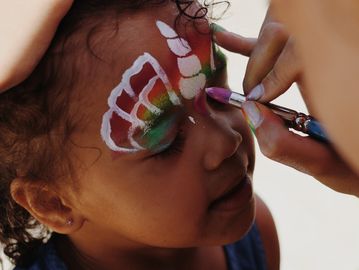 Girl getting a unicorn butterfly facepaint.