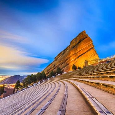 Scenic view of Red Rocks Amphitheater with vibrant sunset sky.