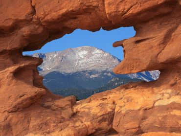 Mountain framed by a natural red rock formation under a clear blue sky.