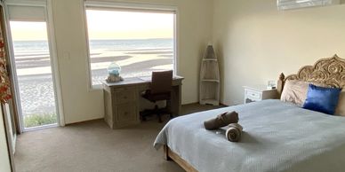 Cozy bedroom with a beach view and a desk facing the large window.