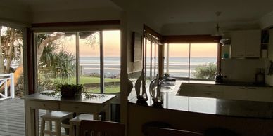 Cozy kitchen and dining area with ocean view at sunset.