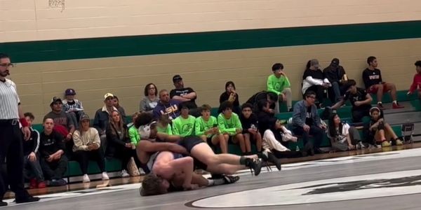 Katy Youth wrestlers in live match at local tournament under referee supervision