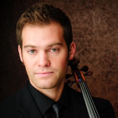 Man holding a violin, dressed formally.