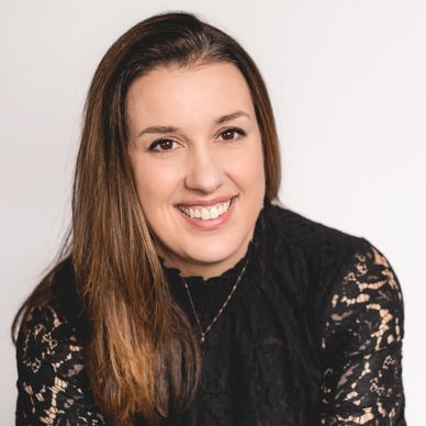 Smiling woman in a black lace top with brown hair.