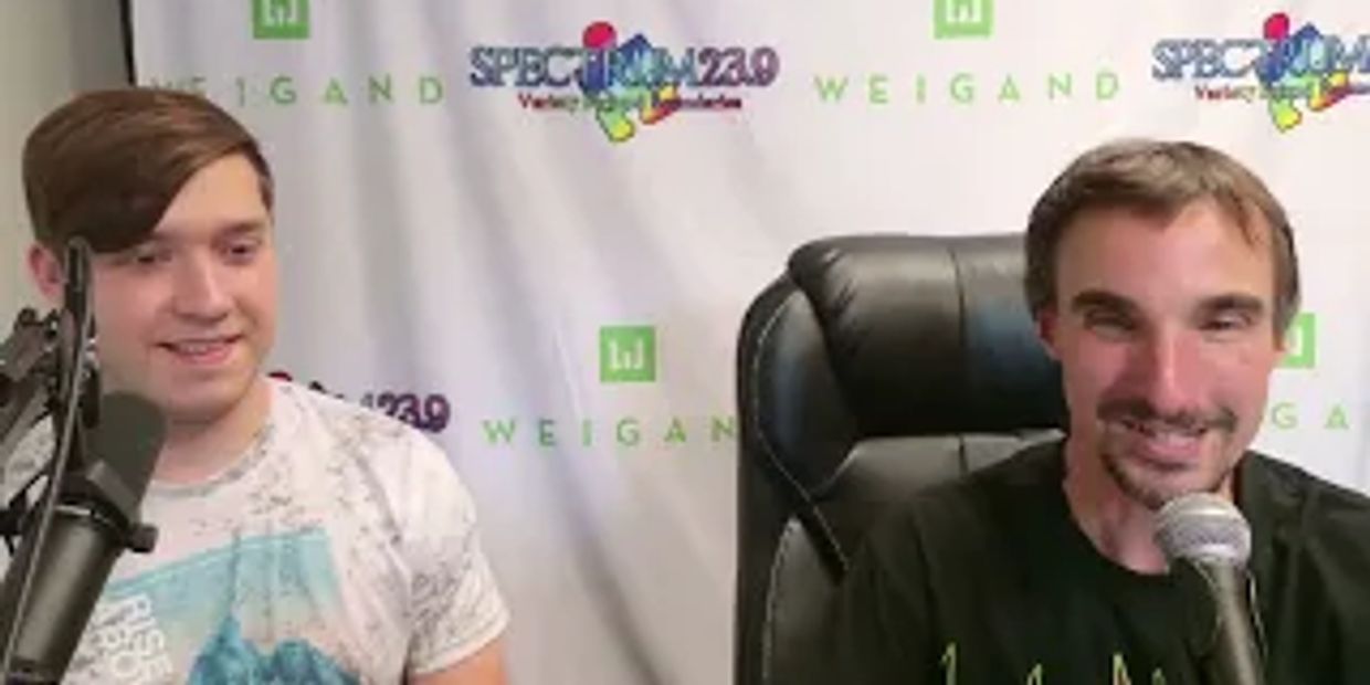 Two men speaking into microphones in a radio broadcast studio.