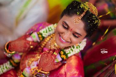 Smiling bride adorned with traditional jewelry and henna.