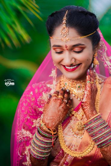 Smiling bride adorned with traditional jewelry and henna.