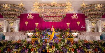 Lavish wedding stage with vibrant floral decorations and a couple in traditional attire.