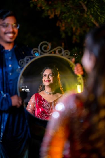 Woman's reflection in a mirror held by a smiling man.