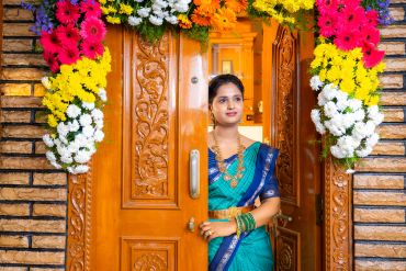 Woman in traditional attire at a decorated wooden door.