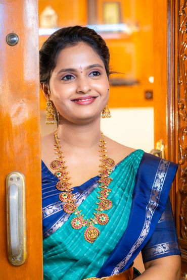 Woman in traditional Indian saree smiling at door.