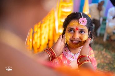 Woman with turmeric paste on face during a traditional ceremony.